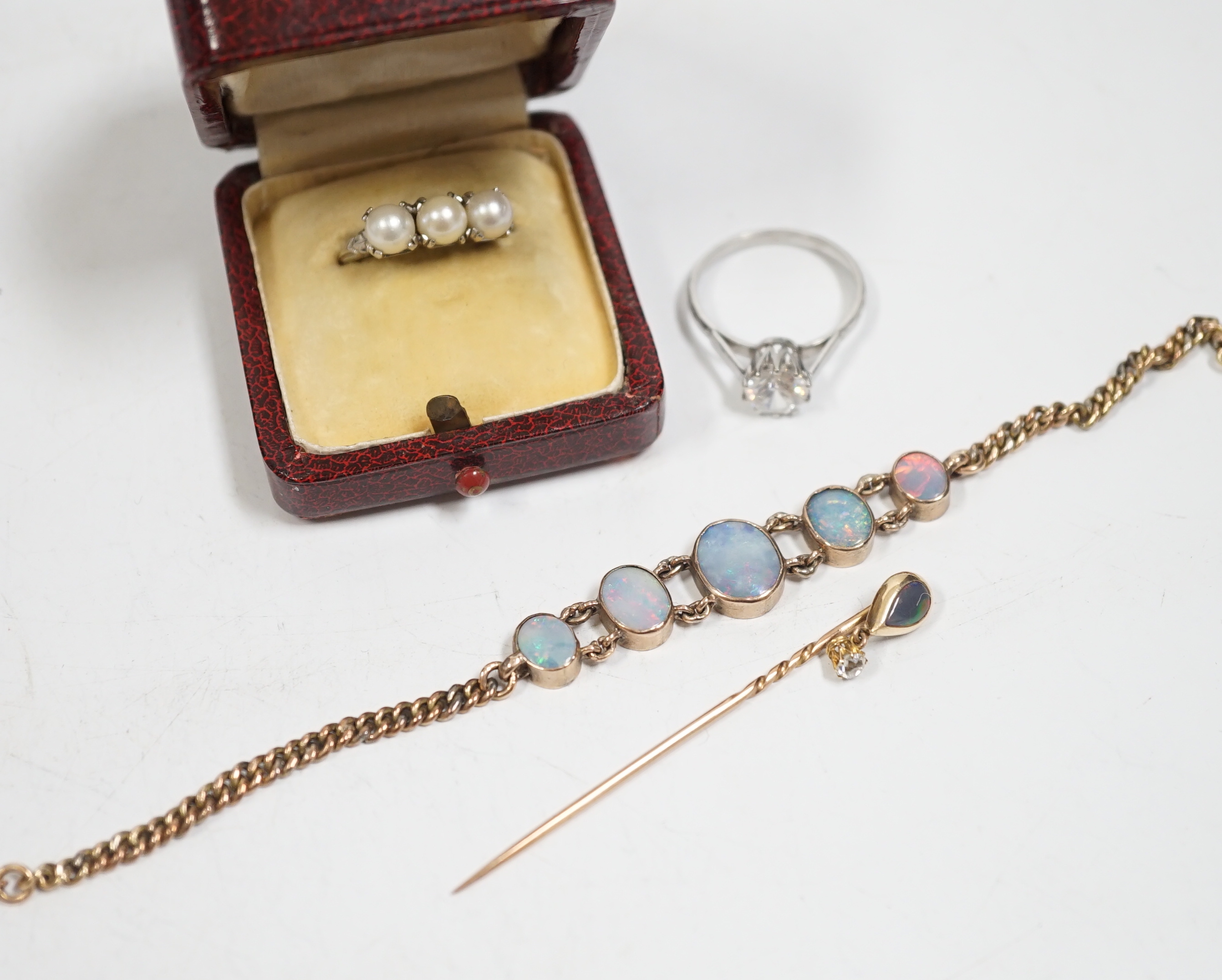 A yellow metal and graduated five stone oval white opal set bracelet, 16.5cm, a yellow metal opal and diamond drop set stick pin, a 14k white metal and three stone culture pearl set ring and a simulated diamond ring.